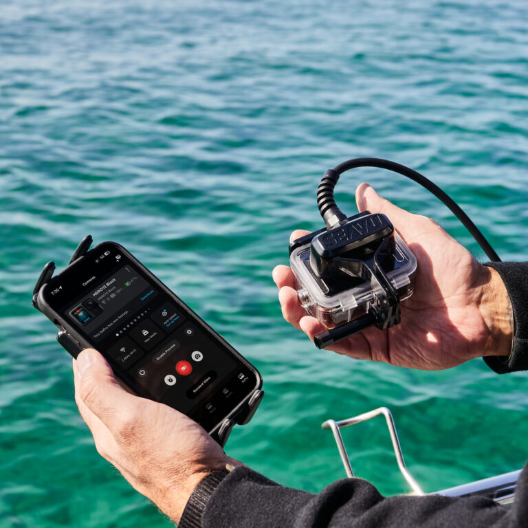 手持运动相机和手机的人使用 Seavu Seeker 连接，接收器和发射器之间有电缆连接